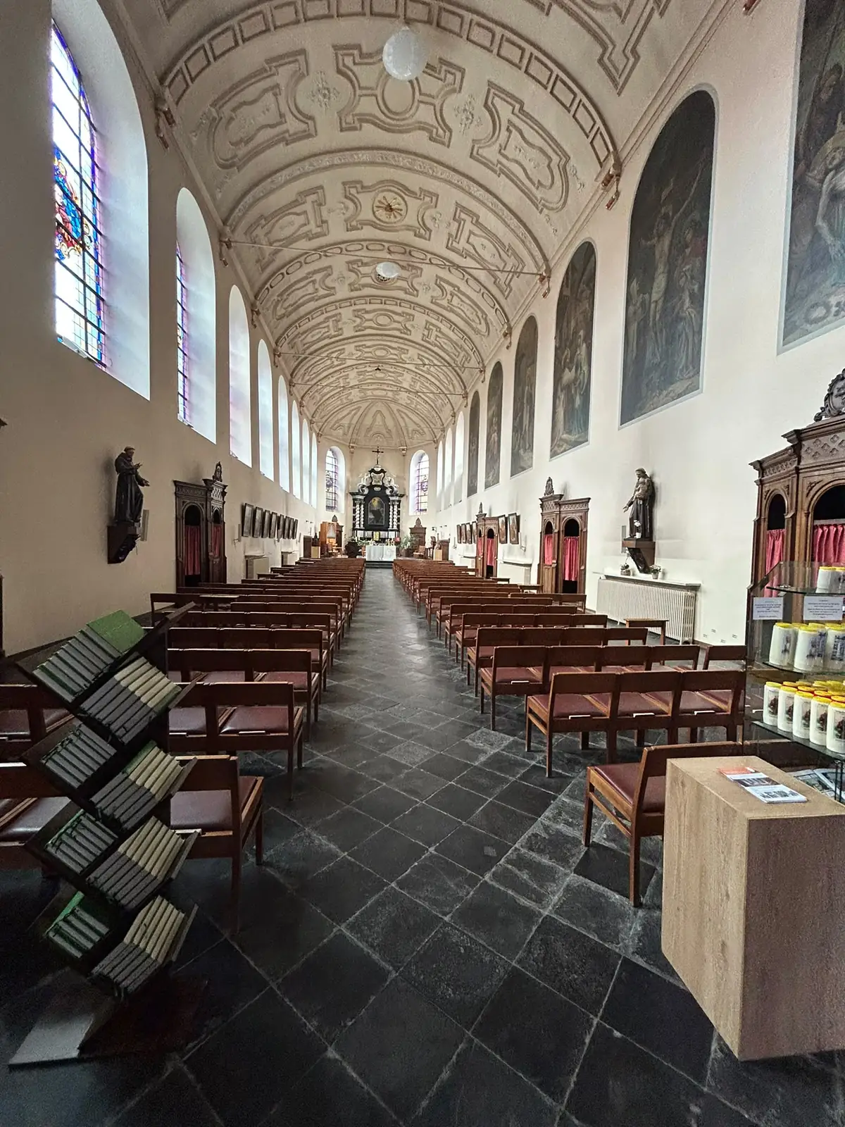 Zijbeuk van de Minderbroederskerk in Hasselt met biechtstoelen, heiligenbeelden en de stoelen vóór de ontruiming